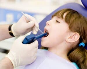 dentist using dental filling gun on kid